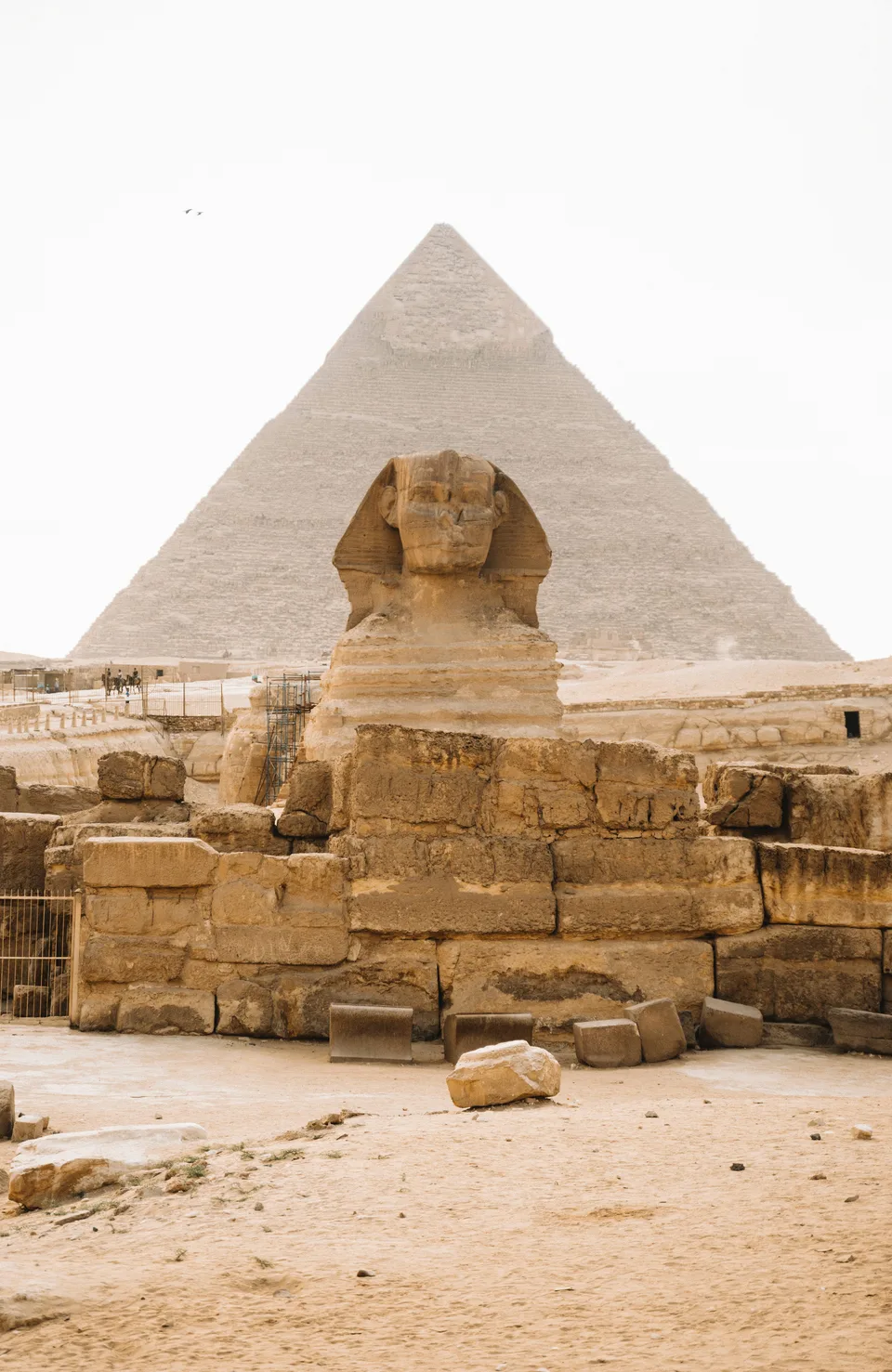 The Sphinx in front of a pyramid under a pale sky