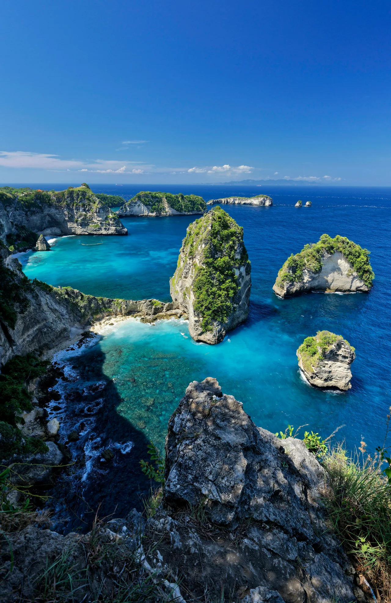 Rocky islands and coastal cliffs below a clear blue sky