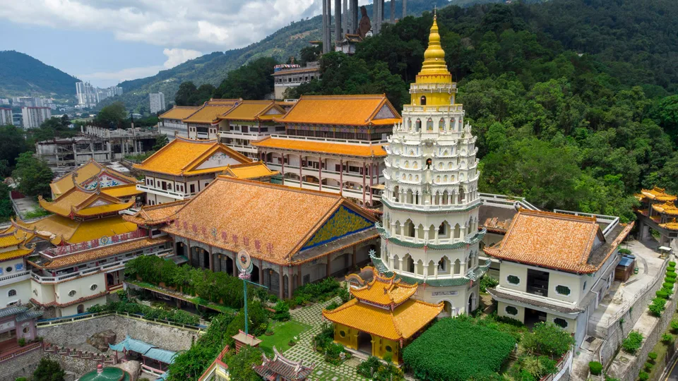 Ornate pagoda and temple roofs among green hills in Penang