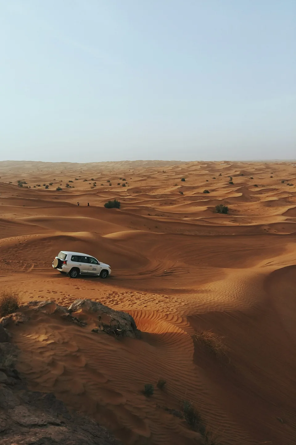 A four-wheel-drive vehicle on a wide expanse of desert dunes