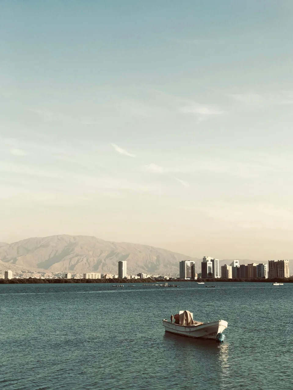 Small boat on calm blue water with mountains behind
