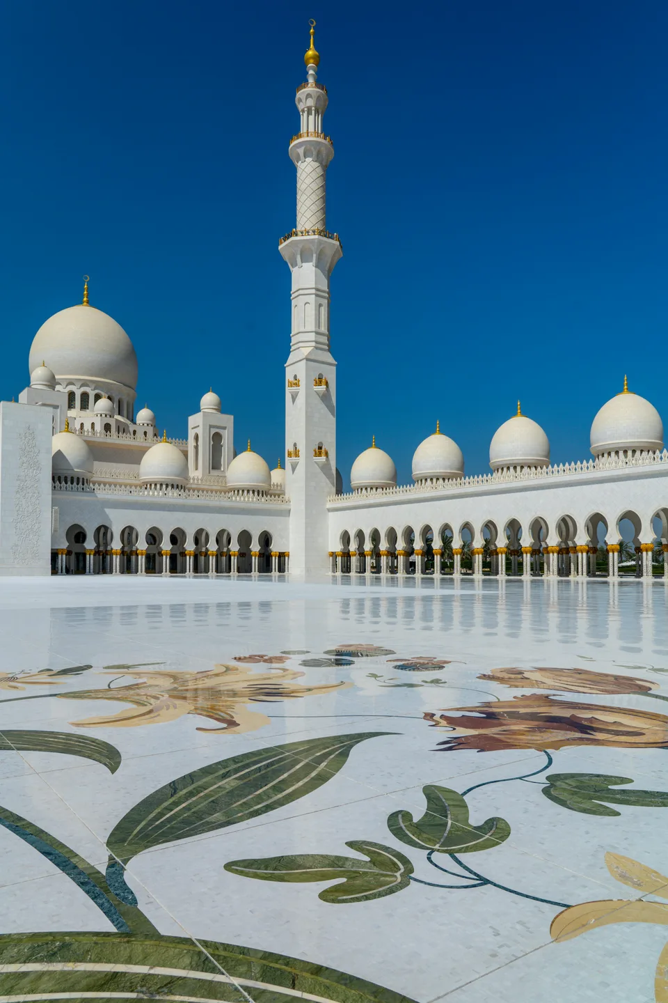 Mosque courtyard and white minaret against a deep blue sky