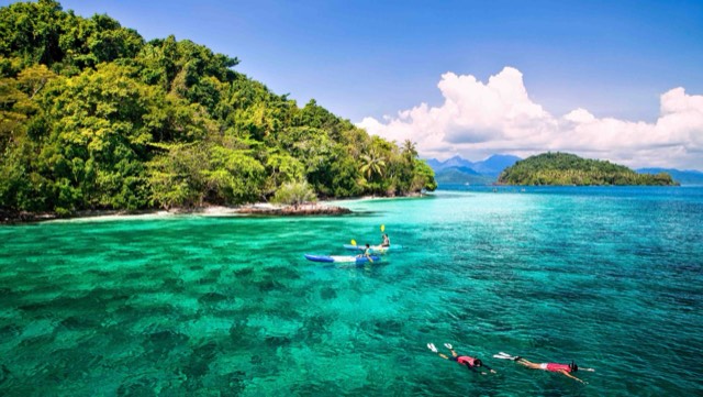 Kayakers and snorkellers over a clear green reef off Ko Lao Ya in Mu Ko Chang National Park, Trat